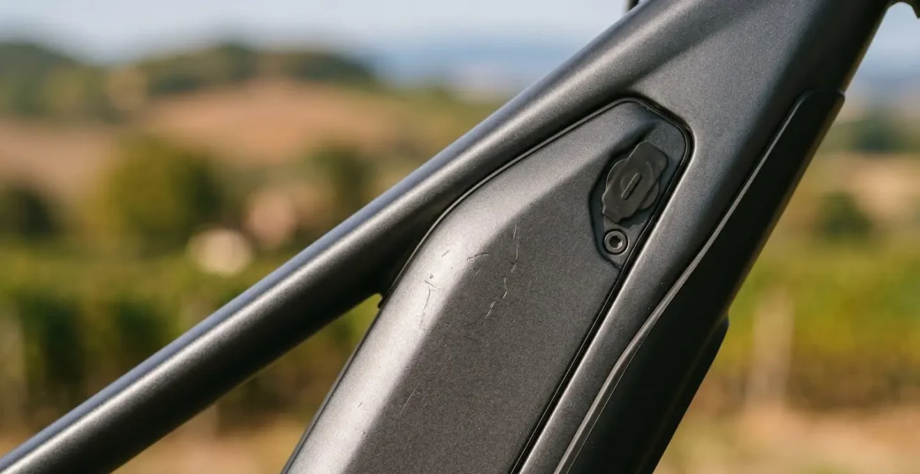 Vue rapprochée d'une batterie de vélo électrique intégrée dans le cadre avec paysage vallonné en arrière-plan