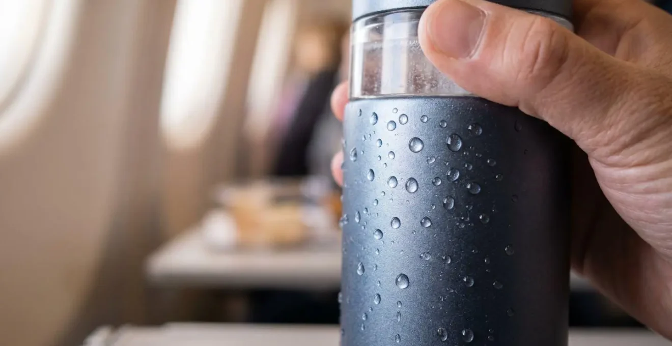 Passager s'hydratant avec une gourde d'eau enrichie en électrolytes pendant un vol